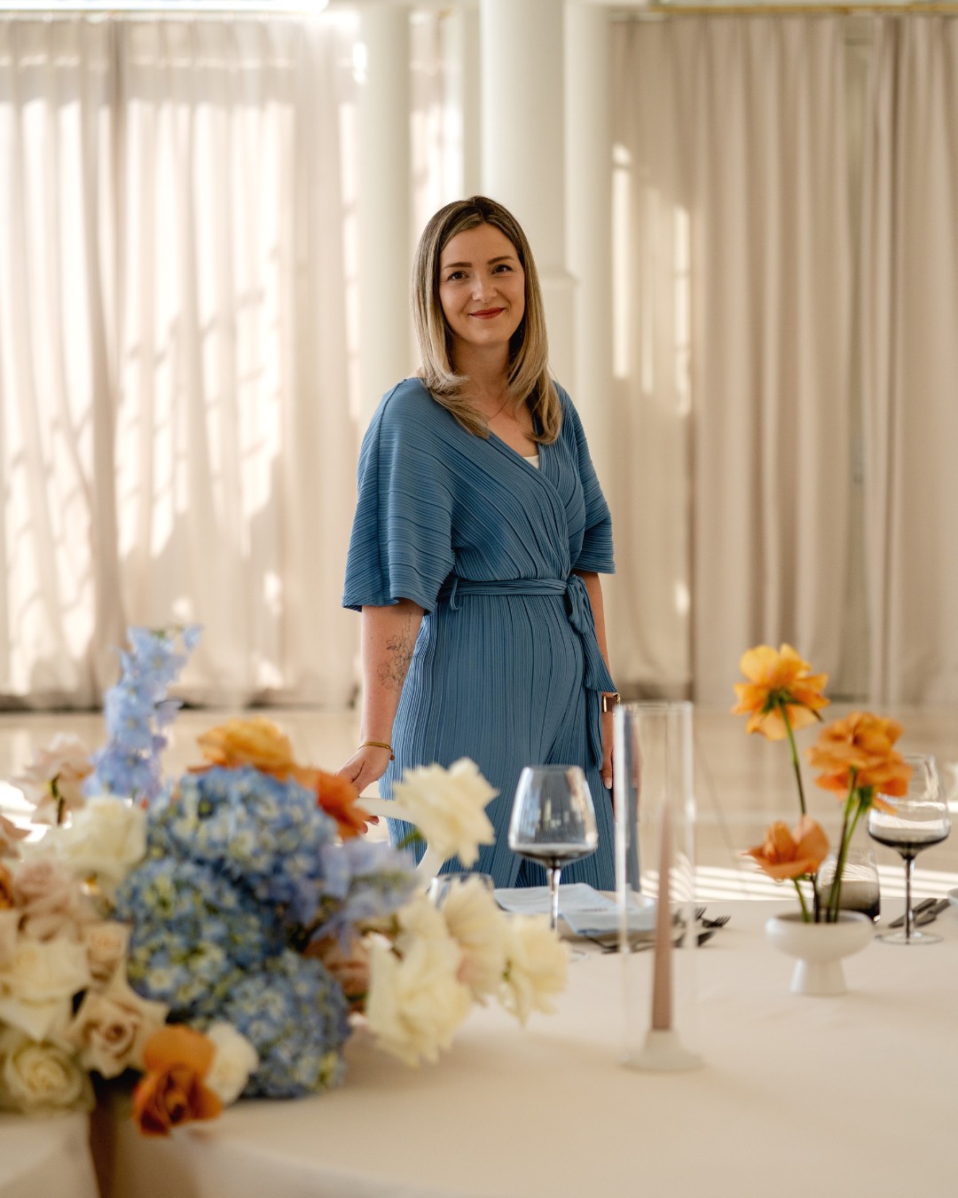 Janine Rhode Traurednerin freie Trauung Hamburg Janine Rhode, Traurednerin für freie Trauung in Hamburg, steht in einem festlich dekorierten Saal zwischen Blumen und gedeckter Tafel