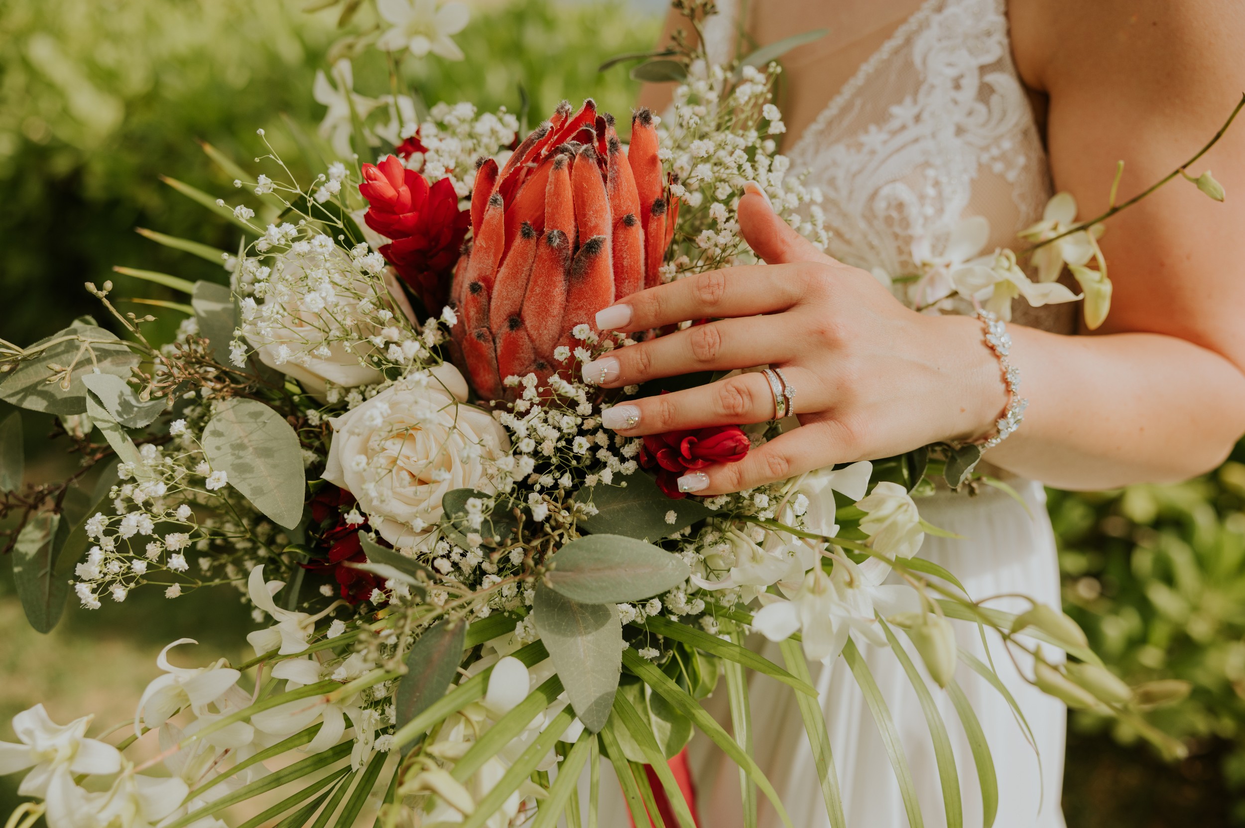 Janine Rhode Traurednerin freie Trauung Hamburg7 Detailaufnahme eines tropischen Brautstraußes mit Protea-Blüte, Eheringen und filigranem Schmuck – Symbol für eine freie Trauung in Hamburg mit hawaiianischer Inspiration