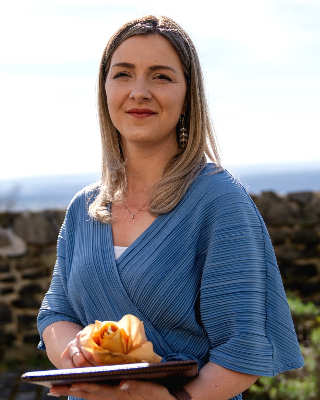 Kinderwillkommensfeier Freie Rednerin Janine bei einer Kinderwillkommensfeier im Freien, mit liebevoller Ausstrahlung und einer gelben Rose in der Hand – ein Moment voller Wärme und Achtsamkeit.